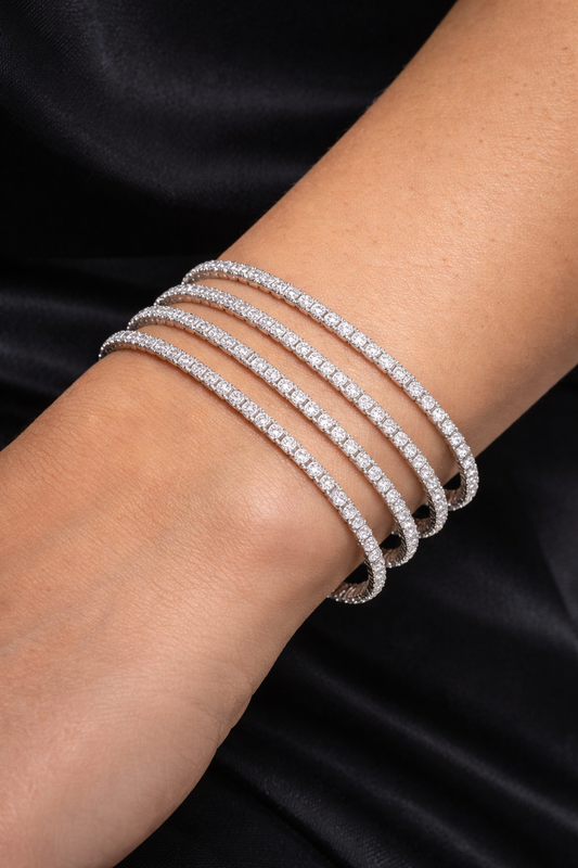 Close-up of a wrist wearing multiple diamond bracelets on a black background