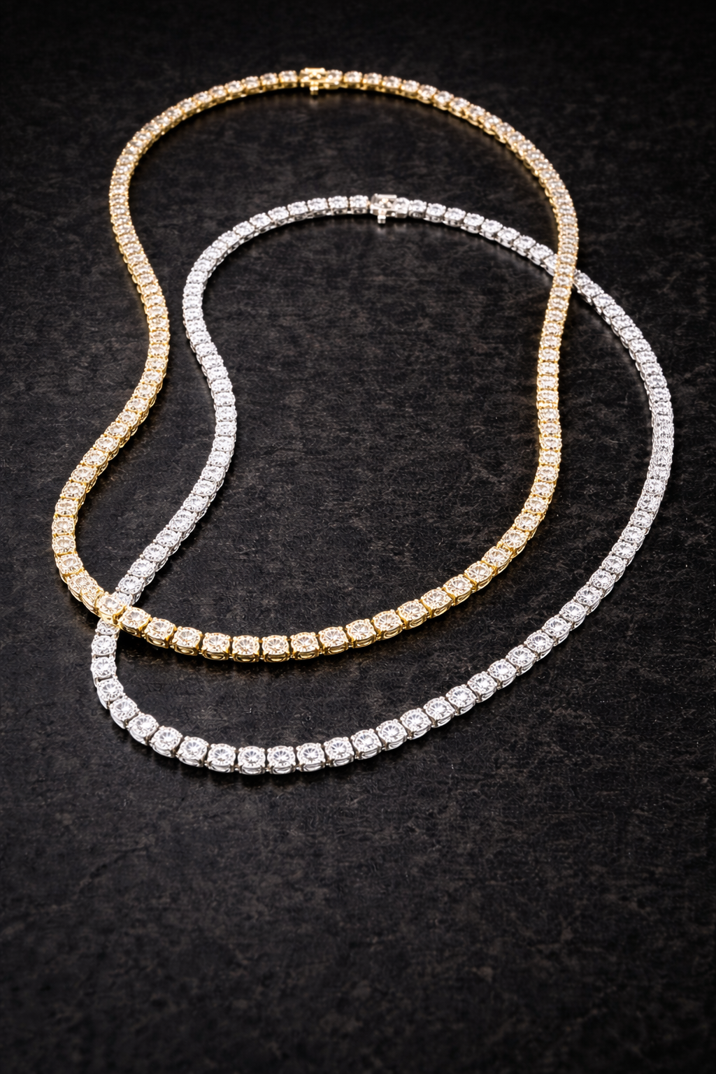 Two diamond necklaces, one gold and one silver, on a black background