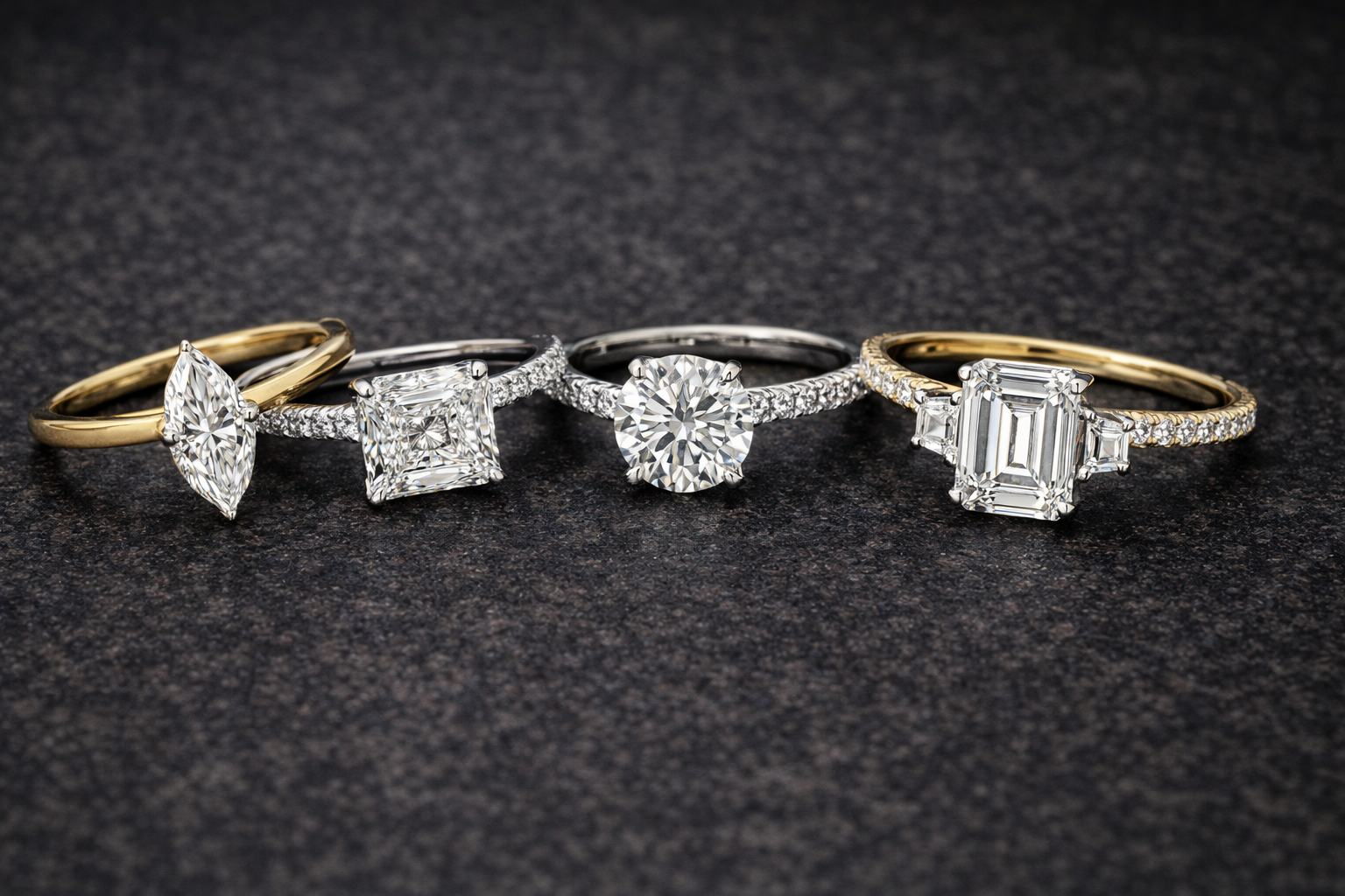 Four diamond rings with different designs on a dark textured background